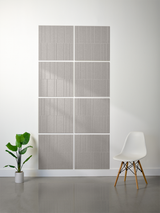 Four gray tiles with vertical line engraving arranged in a 2x2 offset pattern on a wall.