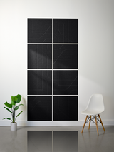 Eight black square tiles arranged in a 2x4 grid with engraved line patterns forming abstract geometric designs.