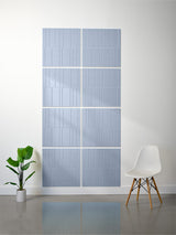 Four light blue tiles with vertical engraved line pattern arranged in offset 2x2 grid on wall.