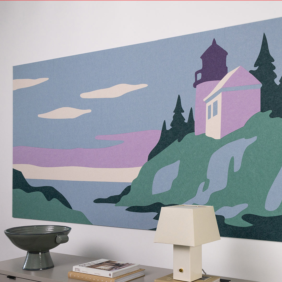 Lighthouse mural on a wall with a lamp and books on a table below.