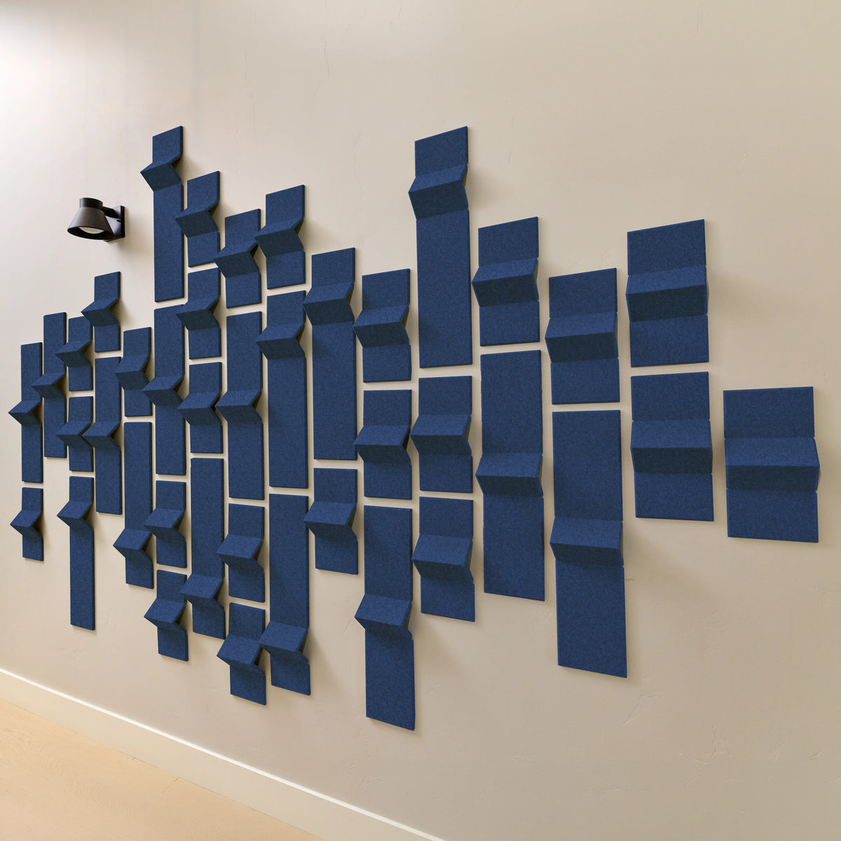 Dark blue acoustic tiles on a hallway wall with slight peaks of dimension