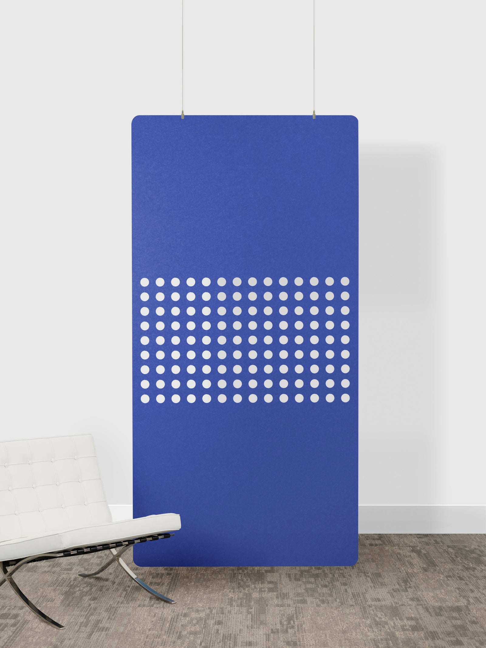 Blue perforated panel on a white wall with a chair in the foreground