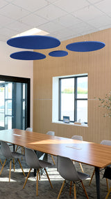 Four blue oval acoustic baffles suspended from ceiling in modern office meeting room with wooden wall paneling.