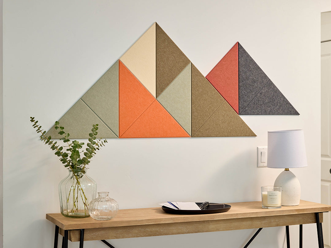 Geometric wall art with triangles in various colors on a white wall above a wooden table.