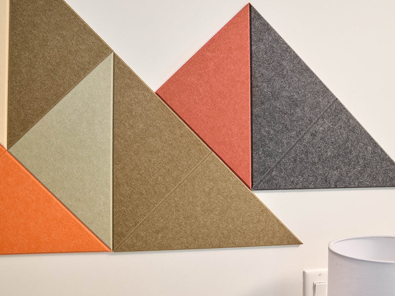 Geometric wall art with triangles in various colors on a white wall above a wooden table.