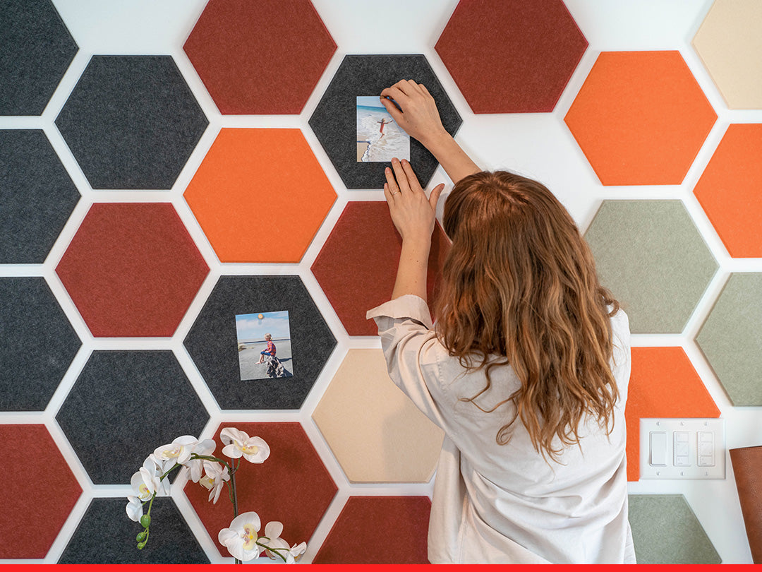 Person arranging hexagonal tiles on a wall with decorative elements.