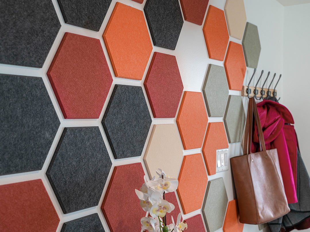 Hexagonal soundproofing panels on a wall with bags and a coat rack.