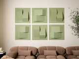 Six sage green tiles with dimensional geometric cutouts and folded shapes arranged in a grid above a tan sofa.