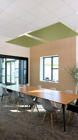 Two olive-green square acoustic panels suspended from ceiling above conference table in office setting.