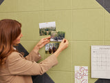 Felt Right tiles in shades of green and black being used a pinboard and a woman pinning photos on to the tiles 