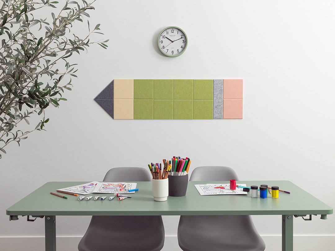 Colorful pencil-shaped wall art above a desk with stationery items.