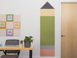 Room with a desk, plant, and wall with colorful tiles shaped like a pencil.