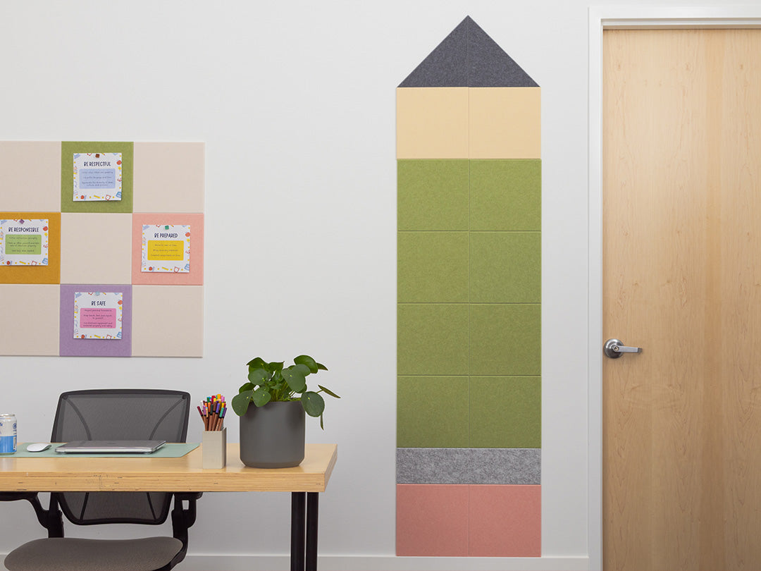 Room with a desk, plant, and wall with colorful tiles shaped like a pencil.