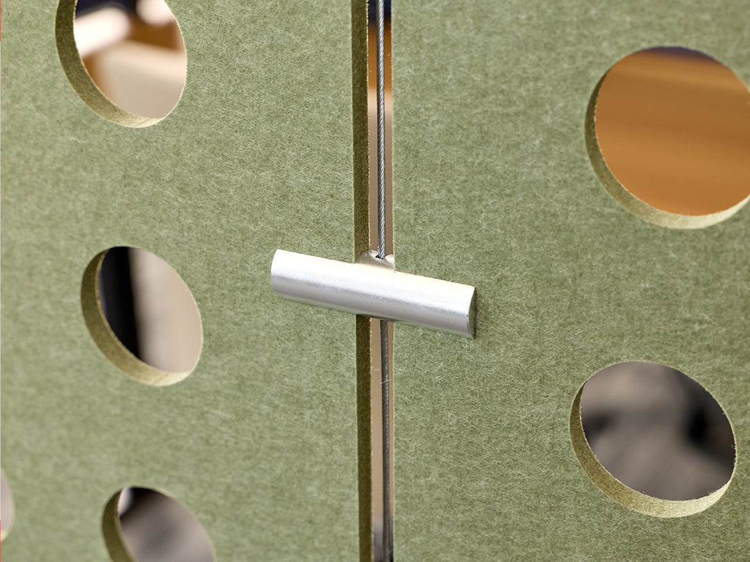 Metallic hardware connector on a green wall with circular cutouts