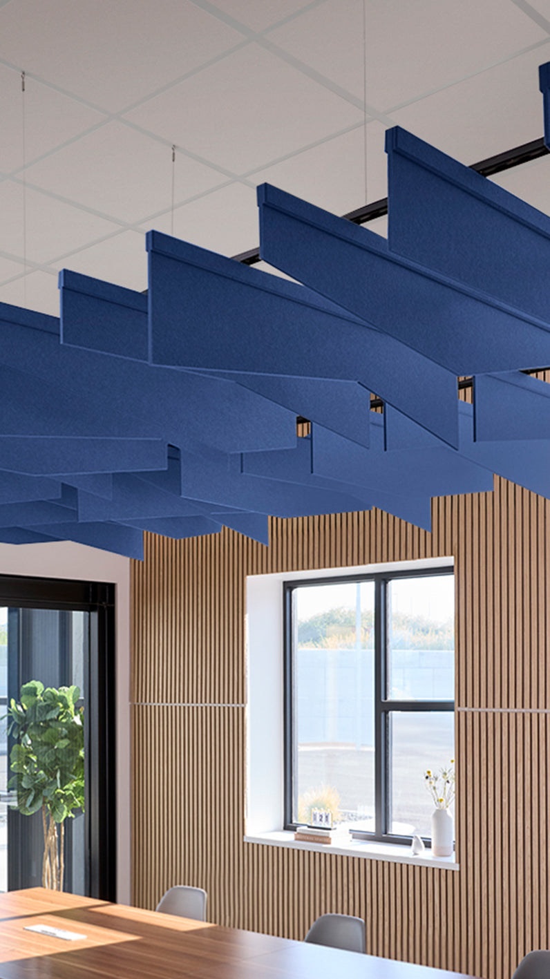 Blue acoustic ceiling blade baffles suspended from the ceiling, installed in a conference room. Felt Right's acoustic blade baffles absorb 65% of sound waves, making office spaces quieter and feel more calm.