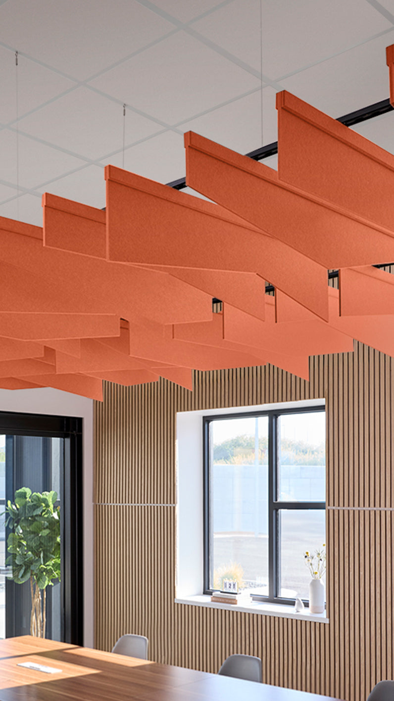 Orange acoustic ceiling blade baffles suspended from the ceiling, installed in a conference room. Felt Right's acoustic blade baffles absorb 65% of sound waves, making office spaces quieter and feel more calm.