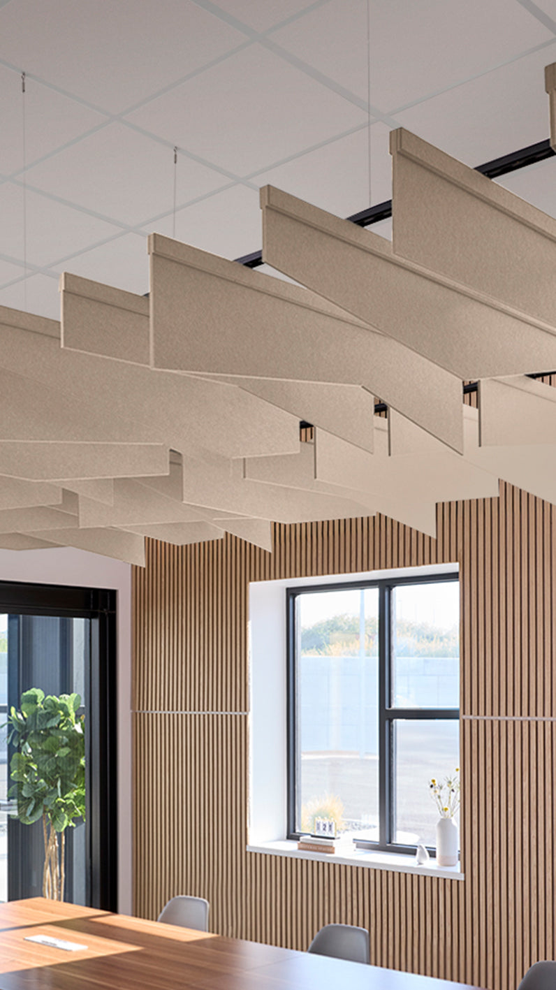 Creamy beige acoustic ceiling blade baffles suspended from the ceiling, installed in a conference room. Felt Right's acoustic blade baffles absorb 65% of sound waves, making office spaces quieter and feel more calm.