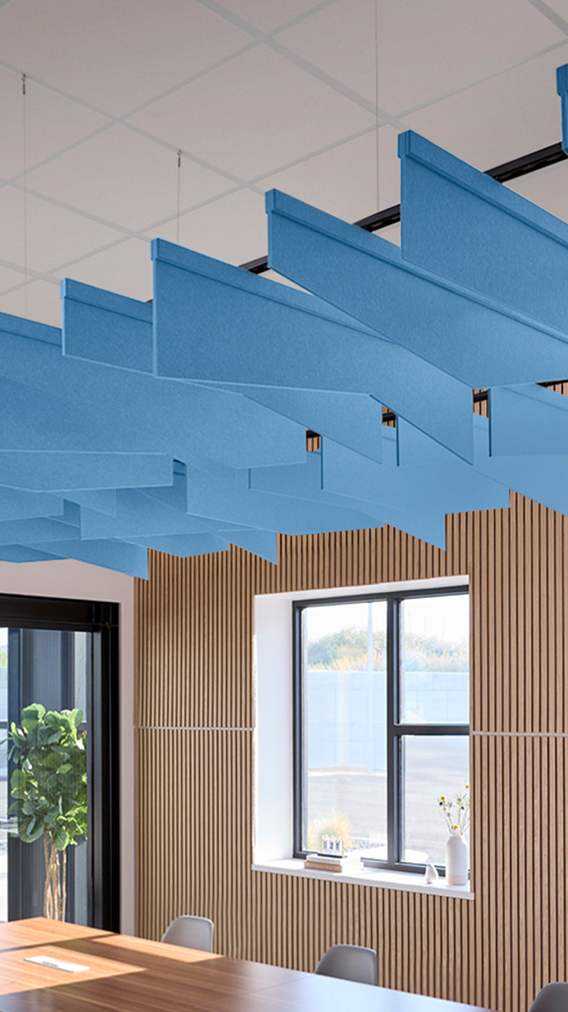 Bright blue acoustic ceiling blade baffles suspended from the ceiling, installed in a conference room. Felt Right's acoustic blade baffles absorb 65% of sound waves, making office spaces quieter and feel more calm.