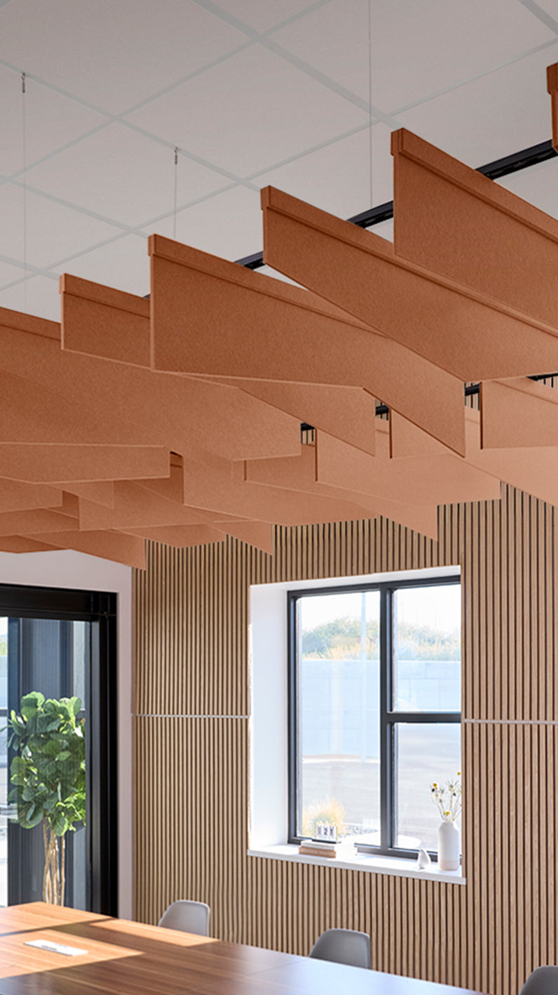 Dark orange acoustic ceiling blade baffles suspended from the ceiling, installed in a conference room. Felt Right's acoustic blade baffles absorb 65% of sound waves, making office spaces quieter and feel more calm.
