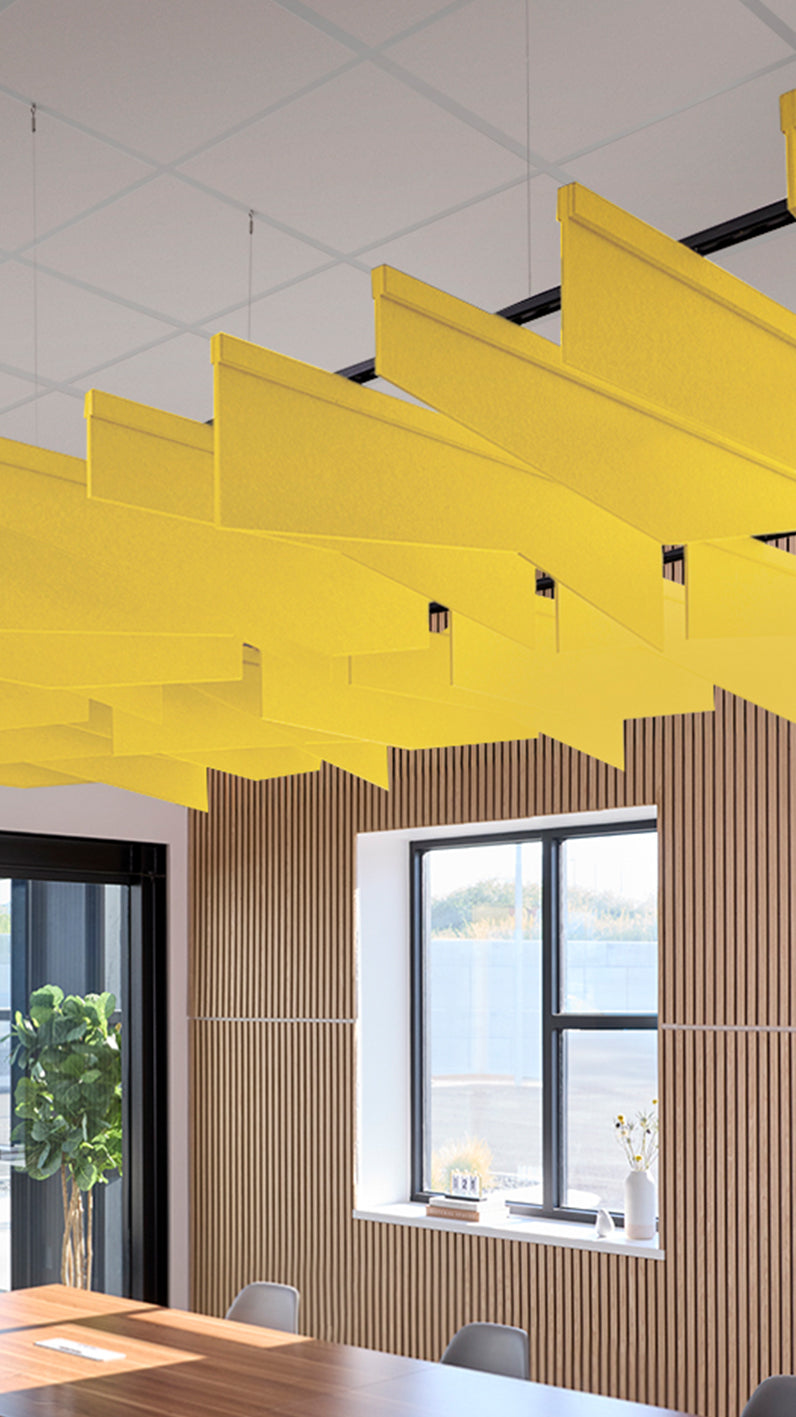Yellow acoustic ceiling blade baffles suspended from the ceiling, installed in a conference room. Felt Right's acoustic blade baffles absorb 65% of sound waves, making office spaces quieter and feel more calm.