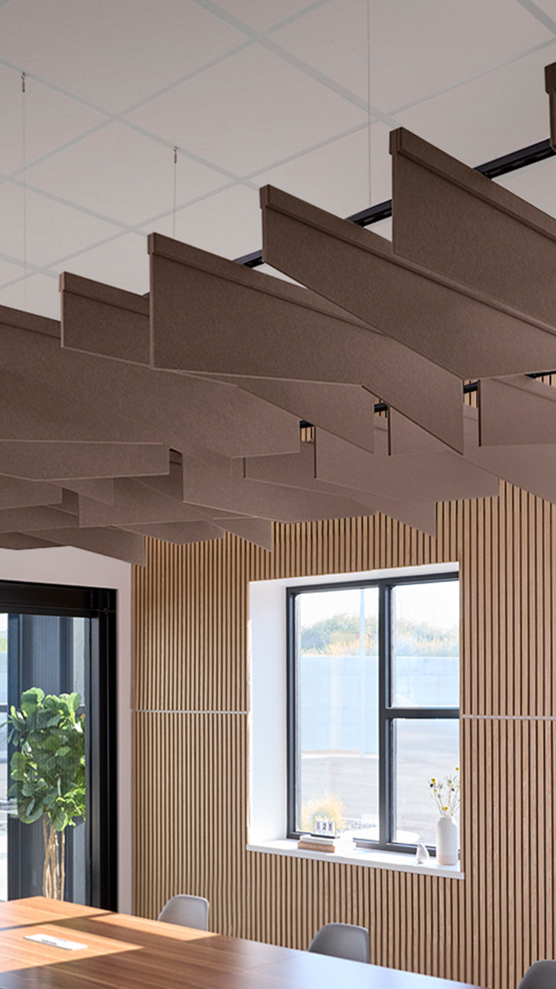 Brown acoustic ceiling blade baffles suspended from the ceiling, installed in a conference room. Felt Right's acoustic blade baffles absorb 65% of sound waves, making office spaces quieter and feel more calm.
