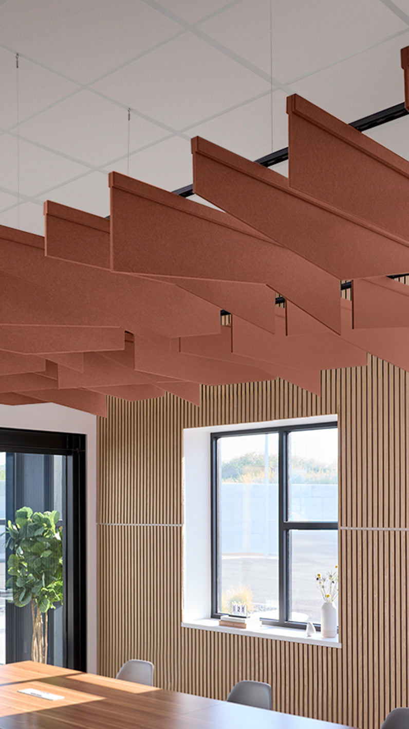 Reddish-brown acoustic ceiling blade baffles suspended from the ceiling, installed in a conference room. Felt Right's acoustic blade baffles absorb 65% of sound waves, making office spaces quieter and feel more calm.