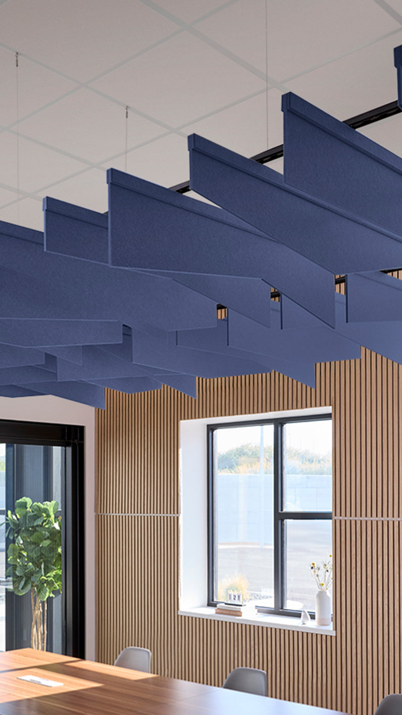 Dark blue acoustic ceiling blade baffles suspended from the ceiling, installed in a conference room. Felt Right's acoustic blade baffles absorb 65% of sound waves, making office spaces quieter and feel more calm.