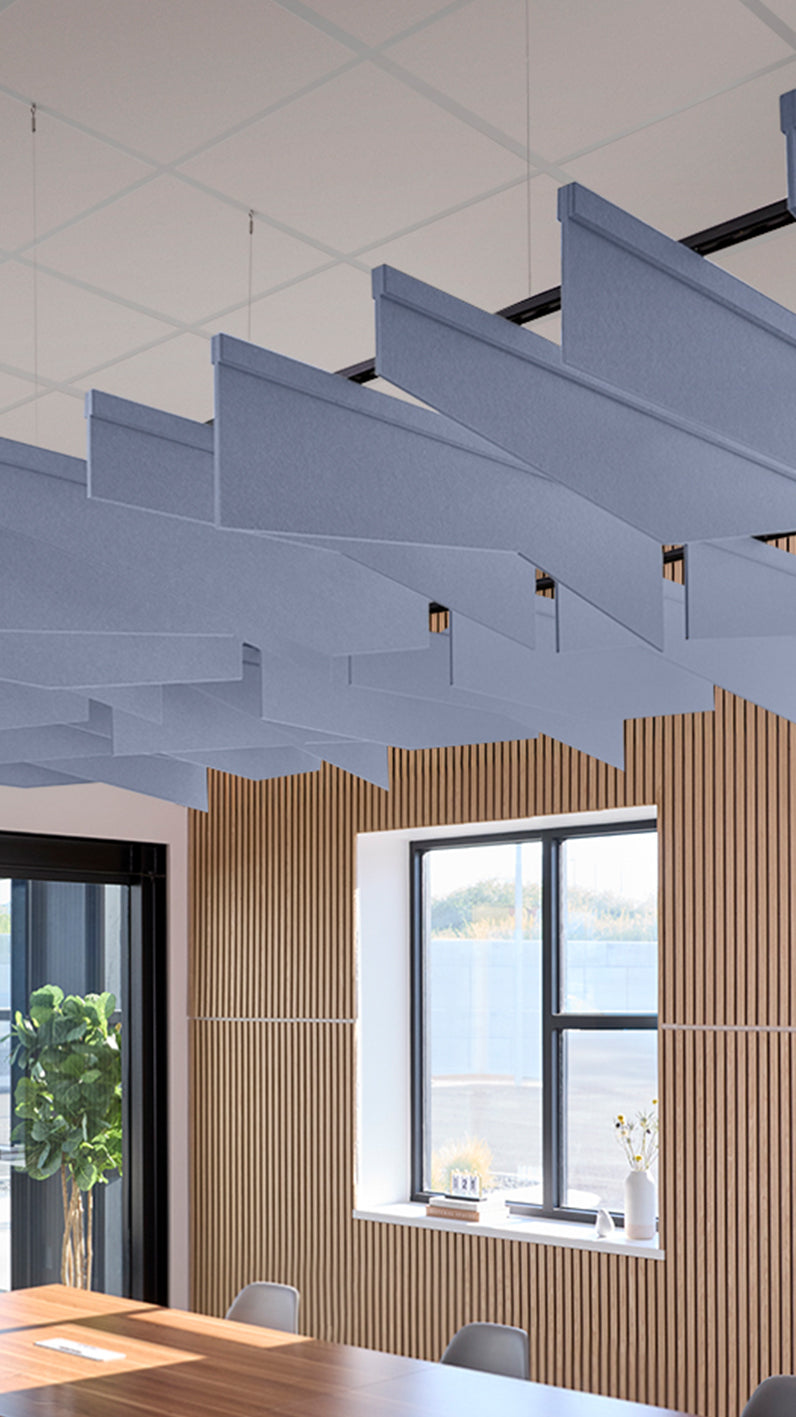 Purplish-blue acoustic ceiling blade baffles suspended from the ceiling, installed in a conference room. Felt Right's acoustic blade baffles absorb 65% of sound waves, making office spaces quieter and feel more calm.