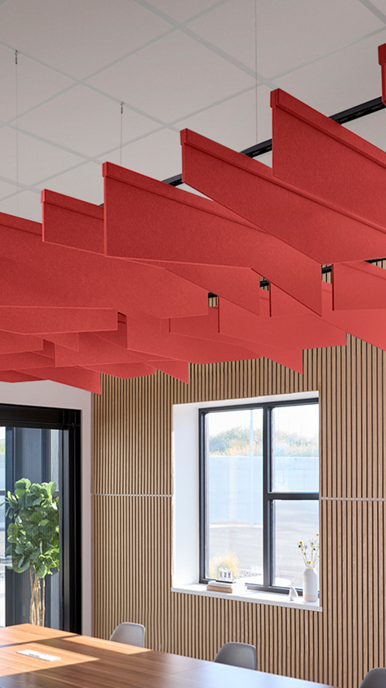 Bright red acoustic ceiling blade baffles suspended from the ceiling, installed in a conference room. Felt Right's acoustic blade baffles absorb 65% of sound waves, making office spaces quieter and feel more calm.
