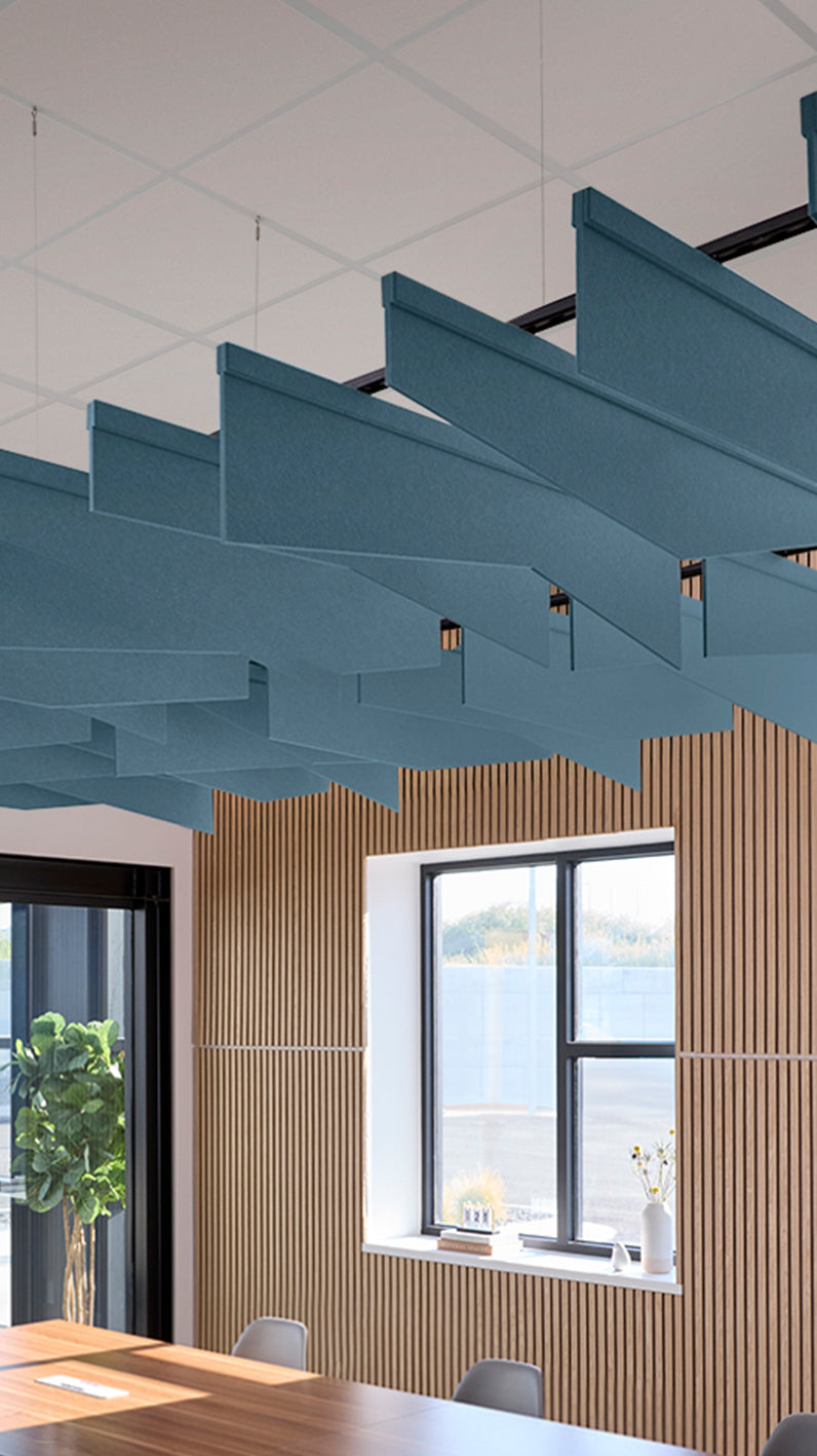 Teal blue acoustic ceiling blade baffles suspended from the ceiling, installed in a conference room. Felt Right's acoustic blade baffles absorb 65% of sound waves, making office spaces quieter and feel more calm.