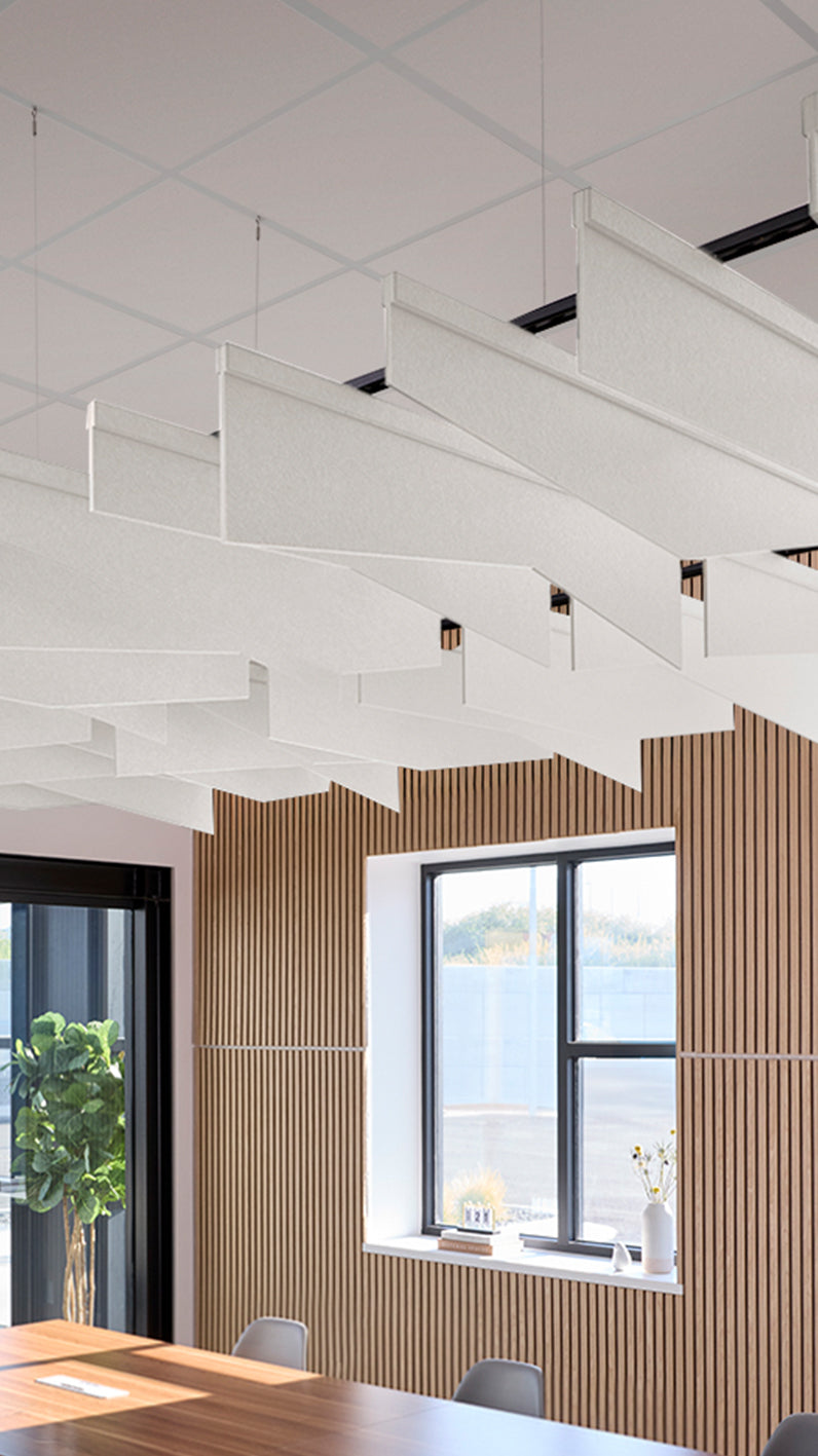 White acoustic ceiling blade baffles suspended from the ceiling, installed in a conference room. Felt Right's acoustic blade baffles absorb 65% of sound waves, making office spaces quieter and feel more calm.
