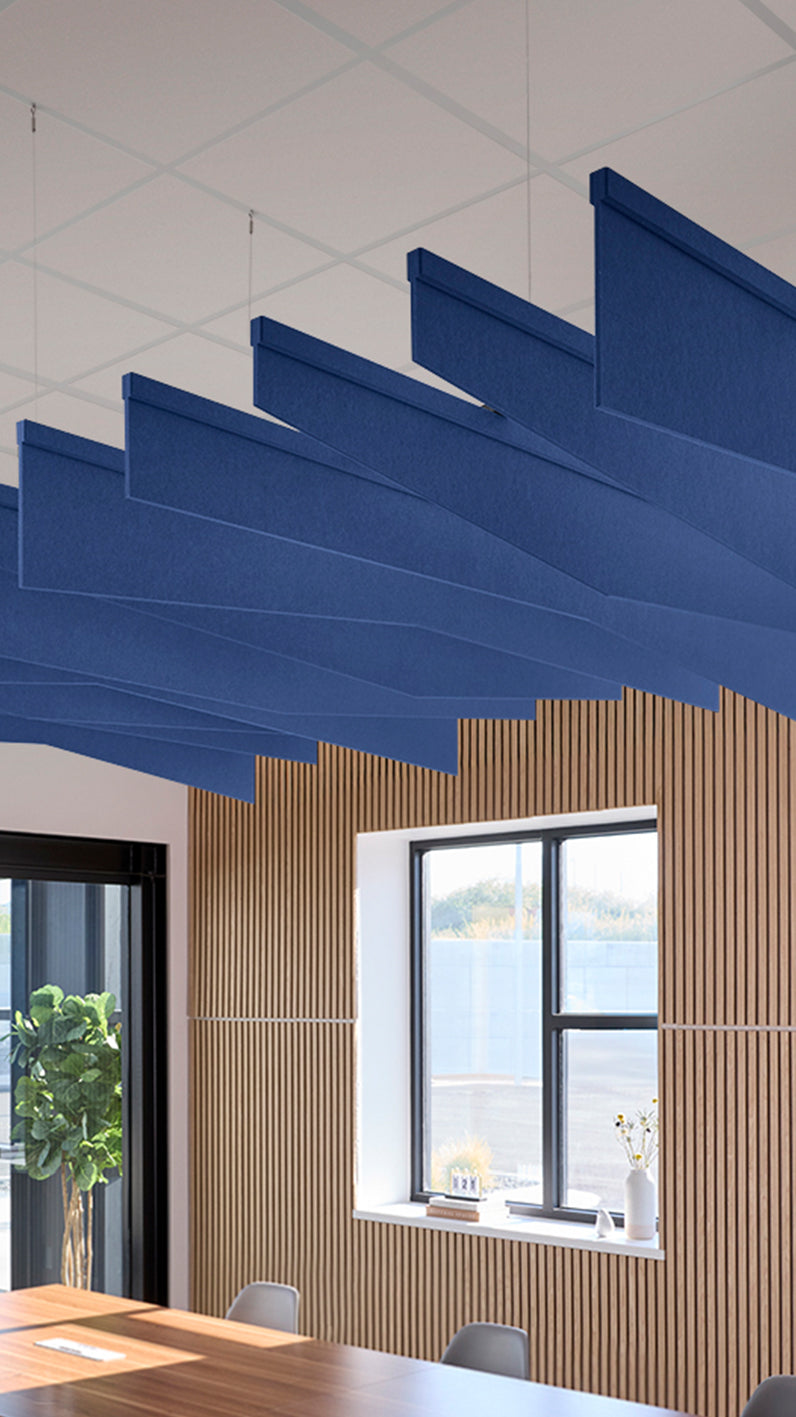 Blue acoustic ceiling blade baffles suspended from the ceiling, installed in a conference room. Felt Right's acoustic blade baffles absorb 65% of sound waves, making office spaces quieter and feel more calm.