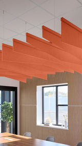 Orange acoustic ceiling blade baffles suspended from the ceiling, installed in a conference room. Felt Right's acoustic blade baffles absorb 65% of sound waves, making office spaces quieter and feel more calm.
