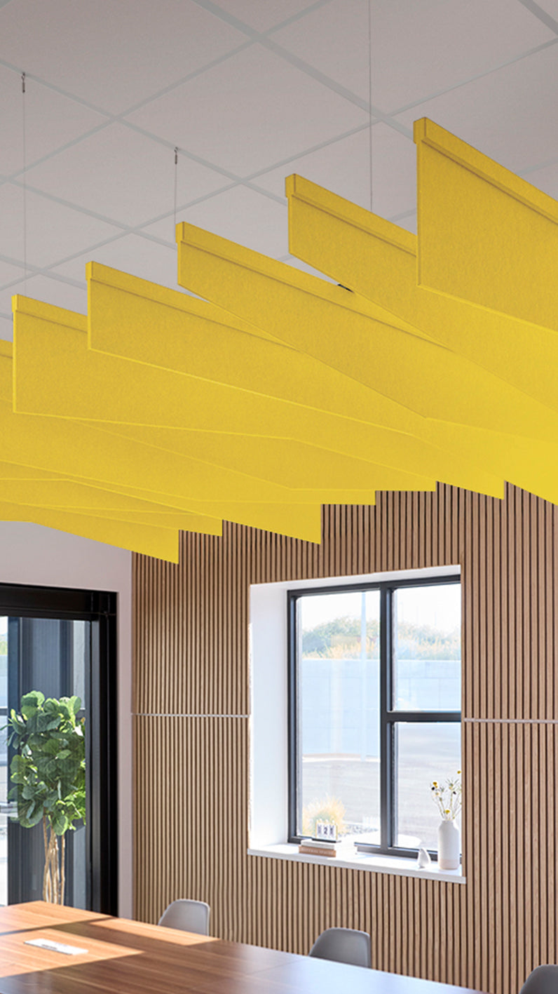 Yellow acoustic ceiling blade baffles suspended from the ceiling, installed in a conference room. Felt Right's acoustic blade baffles absorb 65% of sound waves, making office spaces quieter and feel more calm.