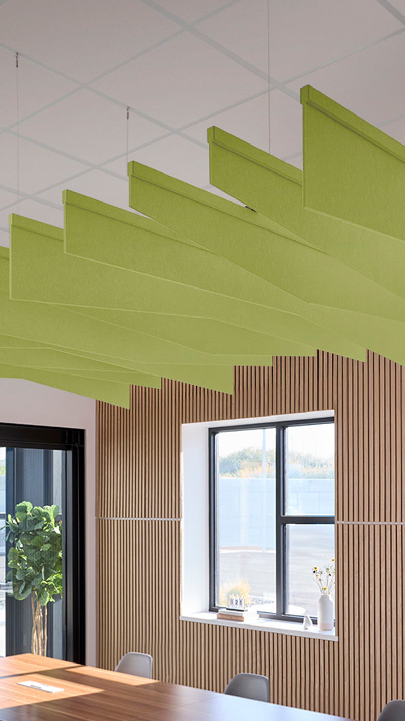 Lime green acoustic ceiling blade baffles suspended from the ceiling, installed in a conference room. Felt Right's acoustic blade baffles absorb 65% of sound waves, making office spaces quieter and feel more calm.