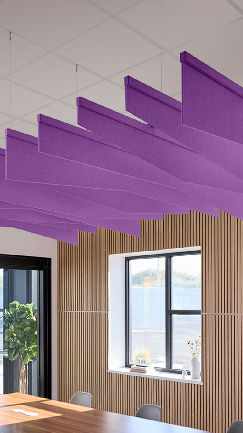 Purple acoustic ceiling blade baffles suspended from the ceiling, installed in a conference room. Felt Right's acoustic blade baffles absorb 65% of sound waves, making office spaces quieter and feel more calm.