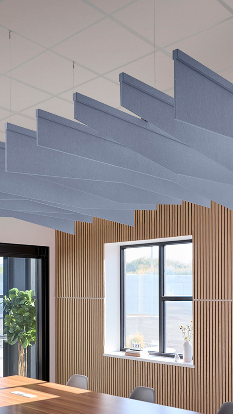Purplish-blue acoustic ceiling blade baffles suspended from the ceiling, installed in a conference room. Felt Right's acoustic blade baffles absorb 65% of sound waves, making office spaces quieter and feel more calm.