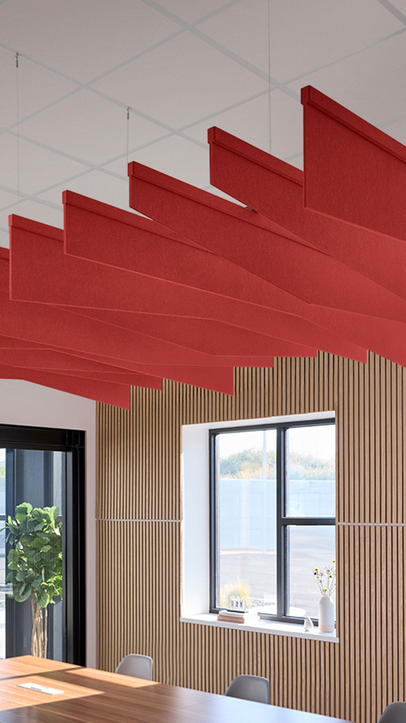 Bright red acoustic ceiling blade baffles suspended from the ceiling, installed in a conference room. Felt Right's acoustic blade baffles absorb 65% of sound waves, making office spaces quieter and feel more calm.