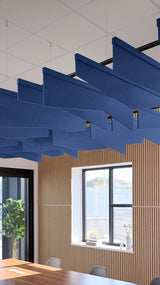 Angled blue acoustic baffles suspended from ceiling in modern interior space with wooden wall paneling.