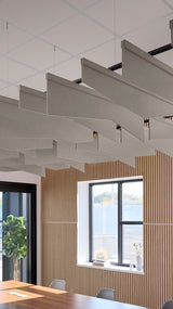 Angled gray fabric acoustic baffles suspended from ceiling in modern office space with wood paneling and windows.