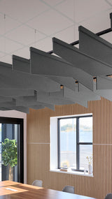 Dark gray angled acoustic baffles suspended from ceiling in modern office space above wooden wall paneling.