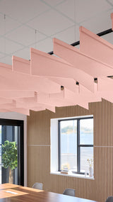 Pink angled acoustic baffles suspended from ceiling in tiered rows above interior workspace.