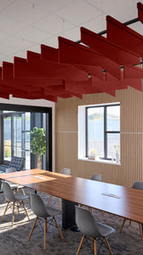 Red angled acoustic baffles suspended from ceiling in modern office space above conference table.