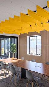 Yellow angled acoustic baffles suspended from ceiling in modern office conference room with wooden table and chairs.