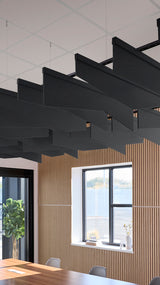 Black angled acoustic baffles suspended from ceiling in modern office space above wooden wall paneling.