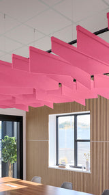 Pink angled acoustic baffles suspended from ceiling in office space above wood-slat wall paneling.
