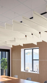Multiple angled cream and white fabric acoustic baffles suspended from ceiling in modern office space.
