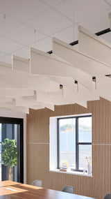Angled beige fabric acoustic baffles suspended from ceiling in modern office space with wood paneling and windows.
