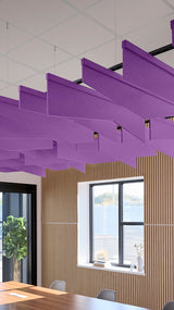 Purple angled acoustic baffles suspended from ceiling in office space with wood paneling and windows.