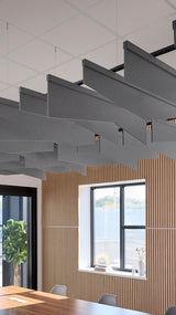 Dark gray angled acoustic baffles suspended from ceiling above wooden wall paneling in modern office space.